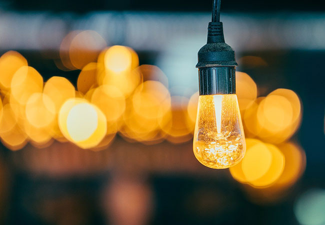 Une ampoule allumée devant des lumières floues, image des idées et du conseil