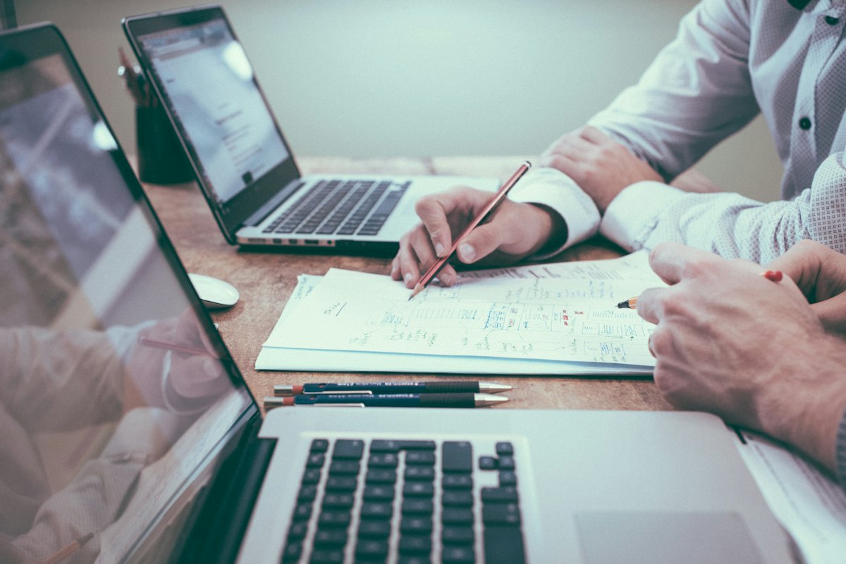 Deux ordinateurs portables et des notes manuscrites sur un bureau pendant un échange de travail