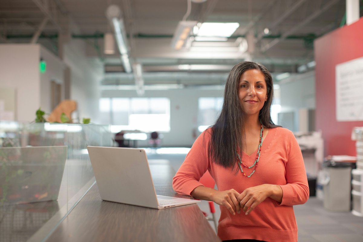 Femme debout devant un bureau lumineux équipé d'un ordinateur